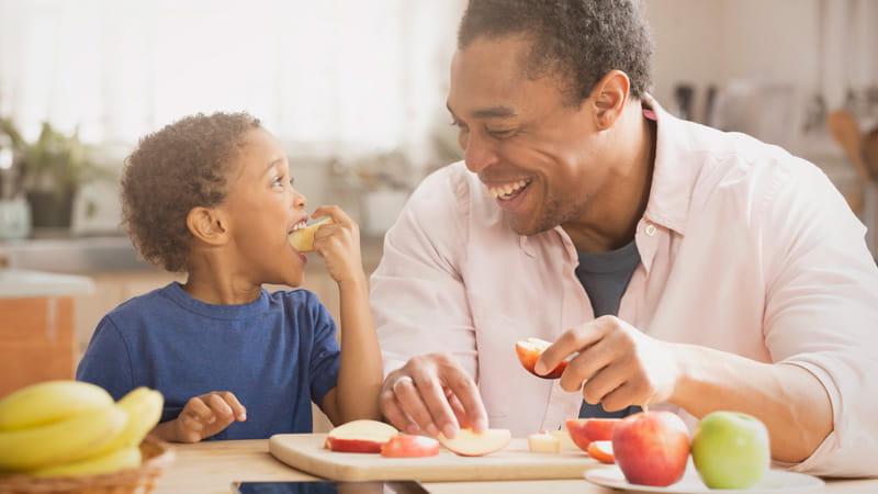 father and son eating apples in kitchen